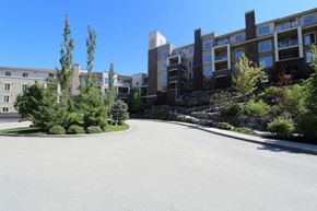 Kelowna condo for rent - A large, empty parking lot in front of a modern building.