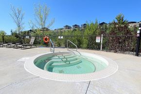 Kelowna condo for rent - A hot tub sits in the middle of a patio surrounded by a black fence.