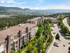Kelowna condo for rent - A large building with a parking lot in front of it.