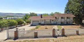 Kelowna apartment for rent - A house with a white fence in front of it.