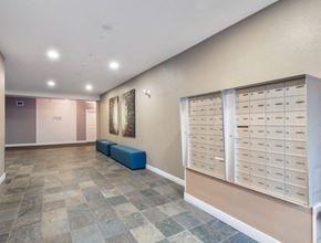 Kelowna condo for rent - A hallway with a bench and a wall of mailboxes.