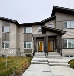Leduc apartment for rent - A modern two-story building with a brown and beige exterior and a front door with a brown door and black steps.