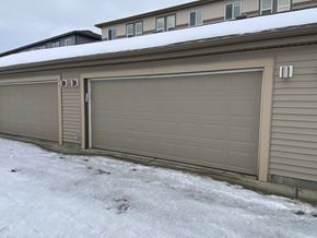 Leduc triplex for rent - A row of tan garage doors in front of a house.