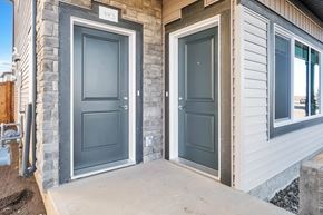 Leduc triplex for rent - A house with a grey door and a white siding wall.