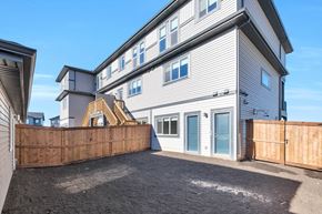 Leduc triplex for rent - A grey house with a wooden fence in front.