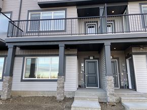 Leduc triplex for rent - A grey house with a balcony and a black door.