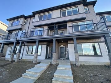 Leduc triplex for rent - A modern two-story residential building with a balcony on the second floor.