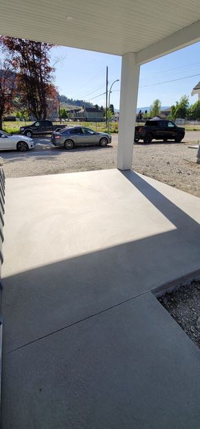 Kelowna apartment for rent - A parking lot with cars and a white building in the background.