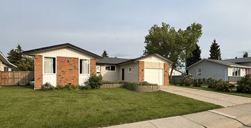 Edmonton apartment for rent - A house with a red brick chimney and a white garage door.