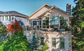 Edmonton apartment for rent - A house with a balcony and a tree with red leaves in front of it.