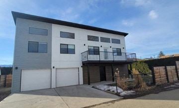 Kelowna apartment for rent - A modern two-story house with a balcony on the second floor.