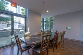 Vancouver condo for rent - A dining room with a table and chairs and a red exit sign above it.