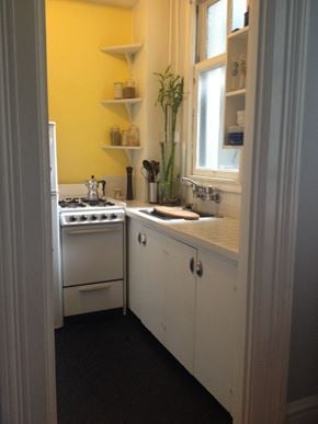 Vancouver apartment for rent - a small kitchen with white cabinets and yellow walls