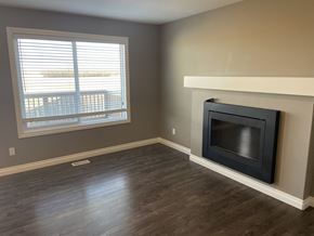 Leduc triplex for rent - A room with a fireplace and a window with blinds.