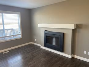 Leduc triplex for rent - A modern living room with a fireplace and wooden flooring.