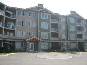 Kelowna condo for rent - a large apartment building with a roundabout in front of it