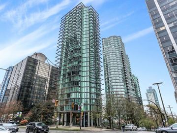 Vancouver condo for rent - A modern glass building stands tall in a city street.