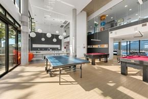 Vancouver condo for rent - A ping pong table is in the middle of a room with a pool table and a foosball table.