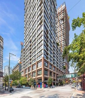 Vancouver condo for rent - A tall building with many windows is in the middle of a city street.