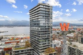 Vancouver condo for rent - A tall building with a W on top stands in front of a cityscape.