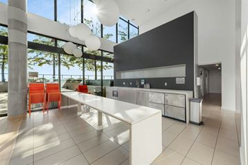 Vancouver condo for rent - A modern kitchen with a long white island and red chairs.