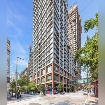 Vancouver condo for rent - A tall building with many windows is in the middle of a city street.