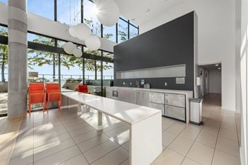 Vancouver condo for rent - A modern kitchen with a long white island and red chairs.