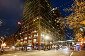 Vancouver condo for rent - A tall building with a lit up W on the side stands next to a shorter building with lit up windows.