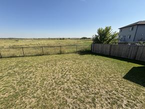 Fort Saskatchewan apartment for rent - A backyard with a fence and a house in the background.