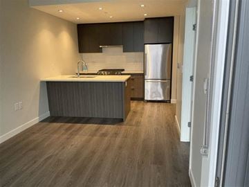 Vancouver condo for rent - A modern kitchen with a stainless steel refrigerator and wooden flooring.