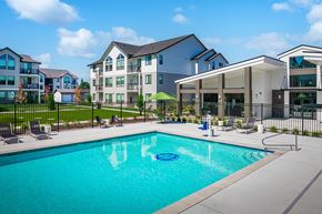 Marysville apartment for rent - A swimming pool in front of a building with a black fence around it.