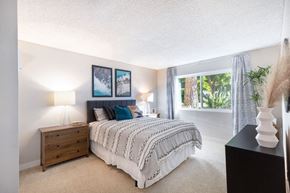Poway apartment for rent - A bedroom with a bed, nightstand, and two pictures on the wall.