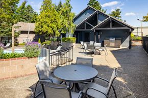 Tigard apartment for rent - A patio with a table and chairs in front of a building.