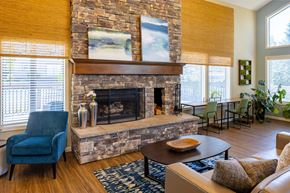 Tigard apartment for rent - A living room with a stone fireplace and a blue chair.
