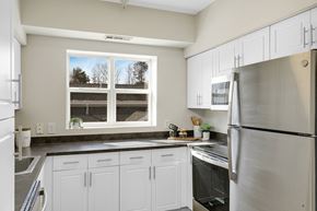 Danvers apartment for rent - A kitchen with white cabinets and a window overlooking a driveway.