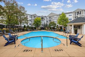 Salem apartment for rent - A large swimming pool surrounded by blue lounge chairs and apartment buildings in the background.