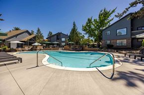 Tigard apartment for rent - A small residential pool surrounded by a concrete patio and houses.