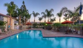 Simi Valley apartment for rent - a blue swimming pool with tables and umbrellas