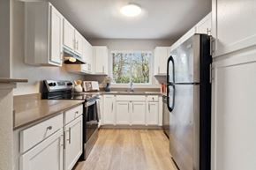 Beaverton apartment for rent - A kitchen with white cabinets and a black refrigerator.