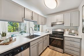 Everett apartment for rent - a kitchen with white cabinets and black appliances and a large window