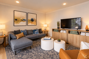 Larkspur apartment for rent - A living room with a grey sofa, a white coffee table, and a television on a wooden cabinet.