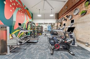 Seattle apartment for rent - a gym with treadmills and other exercise equipment and a wall with a mural
