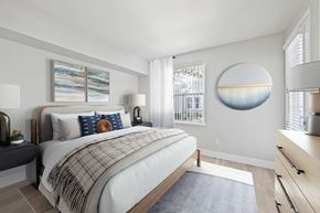 Pleasanton apartment for rent - A bedroom with a large bed and a round mirror on the wall.