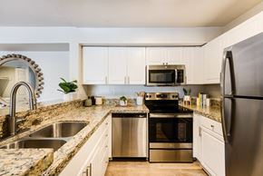 Oceanside apartment for rent - a kitchen with white cabinets and granite countertops