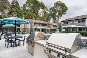 Dublin apartment for rent - A BBQ grill is in the foreground of a patio with chairs and tables.