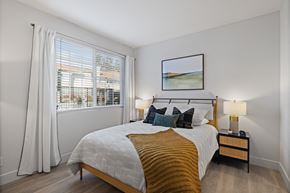 Livermore apartment for rent - A bedroom with a large bed and a window with white curtains.