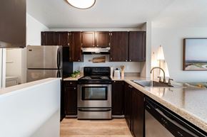Tigard apartment for rent - A modern kitchen with dark wood cabinets and stainless steel appliances.