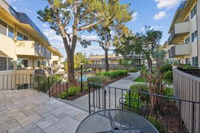 Belmont apartment for rent - a patio with a table and chairs in front of an apartment building