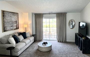 Grove City apartment for rent - A living room with a grey couch, a coffee table, a television, and a painting on the wall.