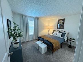 Grove City apartment for rent - A bedroom with a bed, nightstand, and a potted plant.